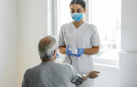Caregiver in long-term care facility taking resident’s blood pressure