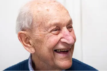 An elderly gentleman smile to someone off-camera