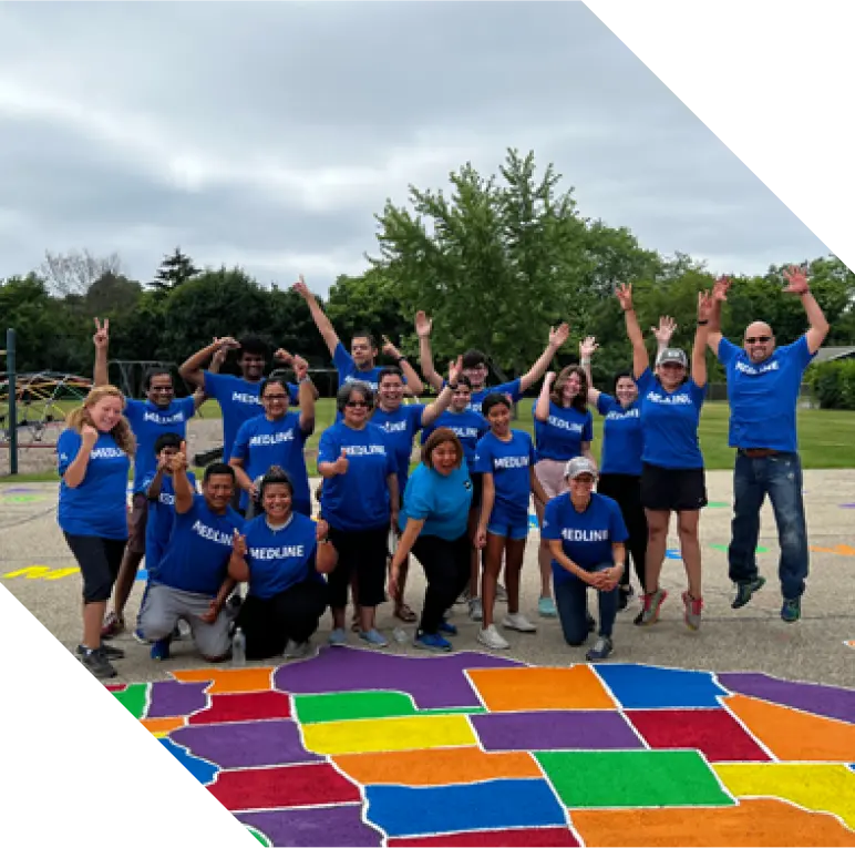 Medline employees in blue shirts posing in front of a colorful map painted on ground outside.