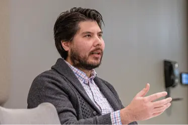 ongoing-engagement A bearded man wearing a gray cardigan presenting information.