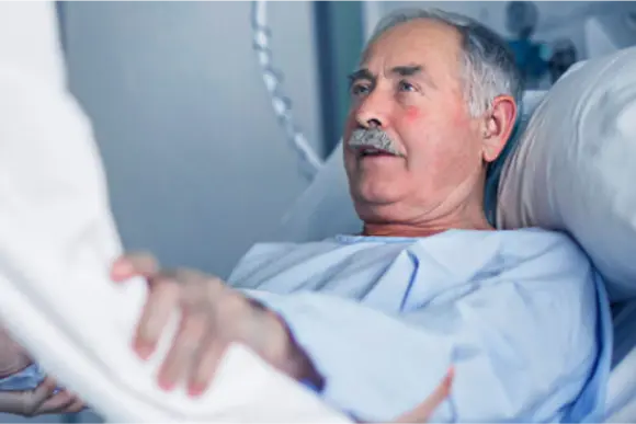 Bedridden male patient grabs caregivers arm