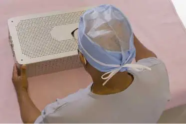 male sterile processing technician with a metal tray ready to be wrapped