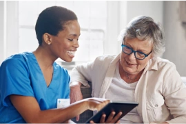 business_solutions_image3 Caregiver sharing information on her tablet with a female coworker