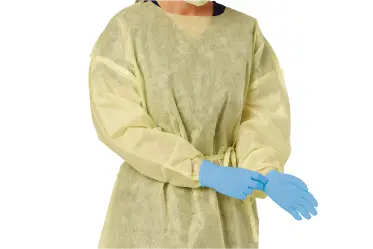 Healthcare worker in medical gown putting on medical gloves