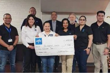A photo of a group of Medline workers holding an oversized donation check to Bethany House