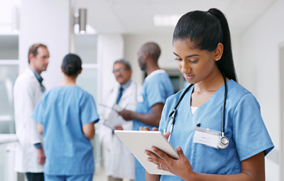 Nurse holding clipboard with group of clinicians behind 